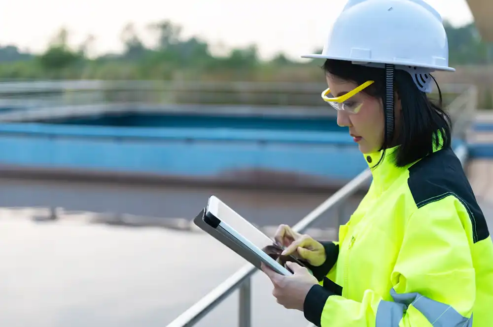 Female engineers working on water treatment plant with tablet device.